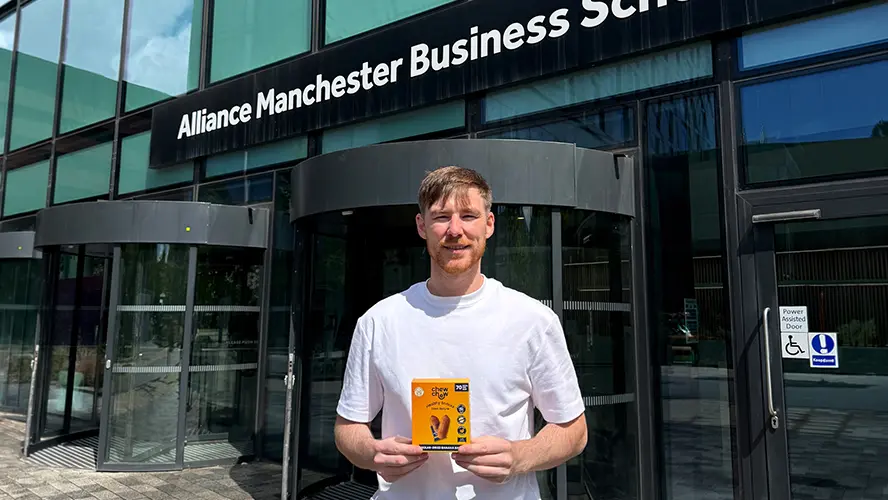 Tom Minnock standing outside Alliance MBS building holding Chew Chew product.