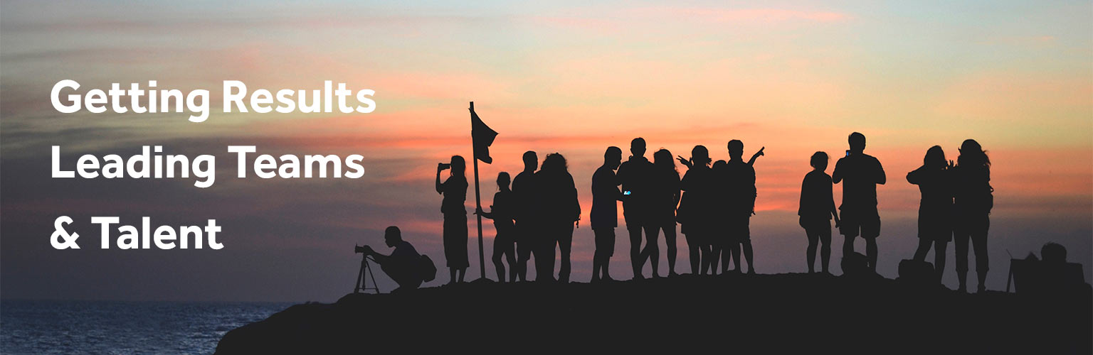 A group of people standing on top of a mountain during sunset 