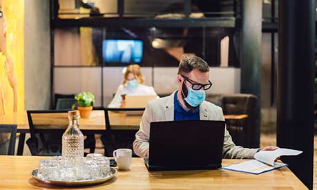 Man working at a desk on a laptop wearing a facemask