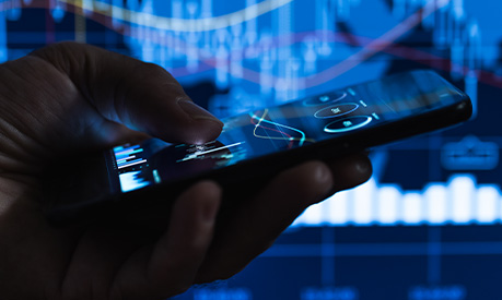 a businessman searching on his smartphone with the stock market in the background