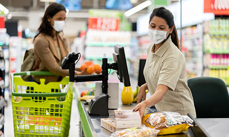 supermarket employee scanning items wearing a face covering