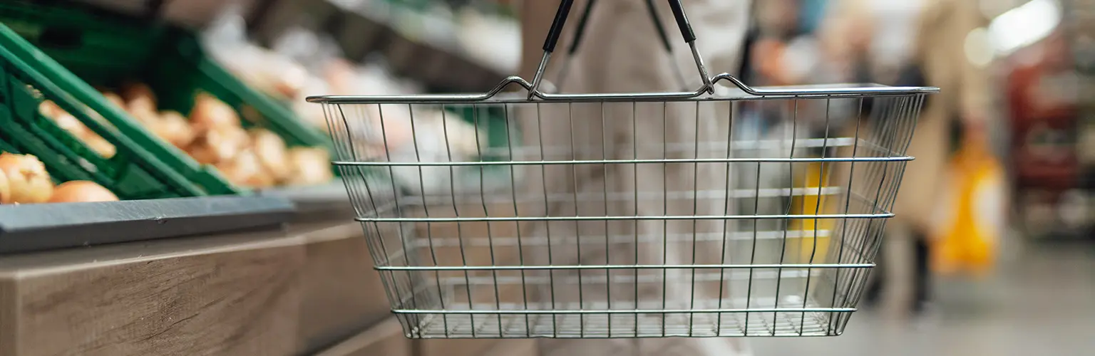 A faceless person holding a shopping basket in a store