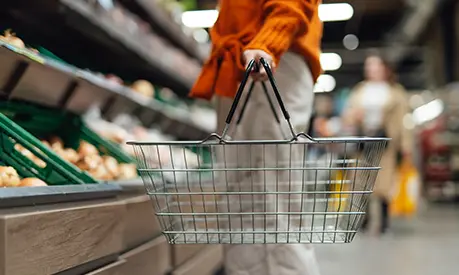 A faceless person holding a shopping basket in a store