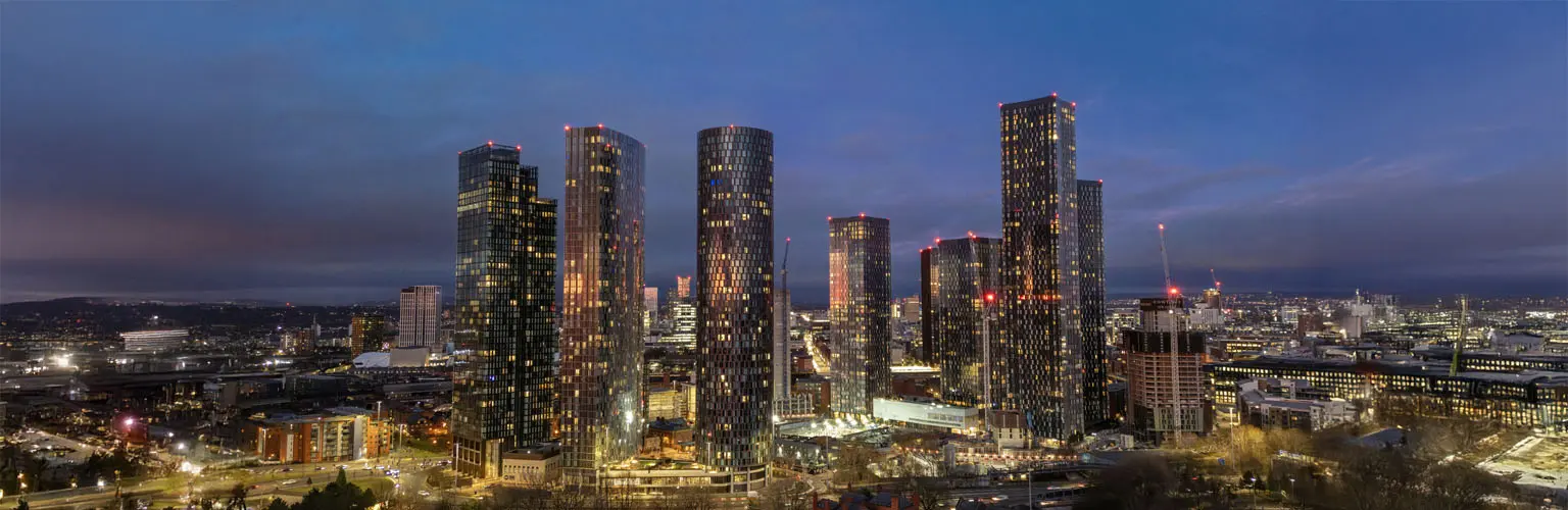 A vibrant cityscape showcasing the illuminated skyscrapers of Manchester at night, emphasizing the urban development and modernity of this iconic UK city.