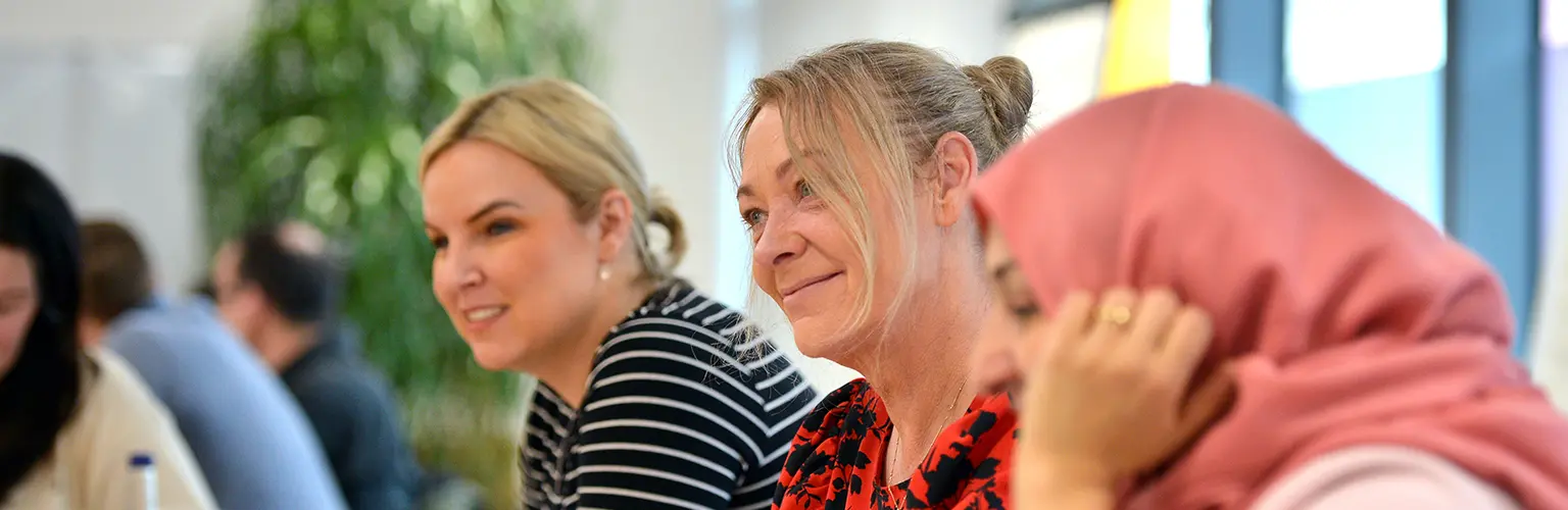 A group of professional women sitting together in a classroom setting.