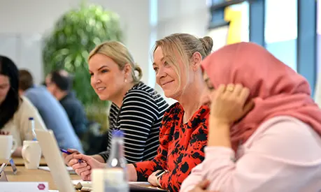 A group of professional women sitting together in a classroom setting