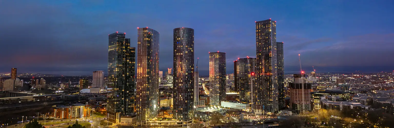 Modern Manchester cityscape at night featuring illuminated skyscrapers.