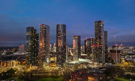 Modern Manchester cityscape at night featuring illuminated skyscrapers.