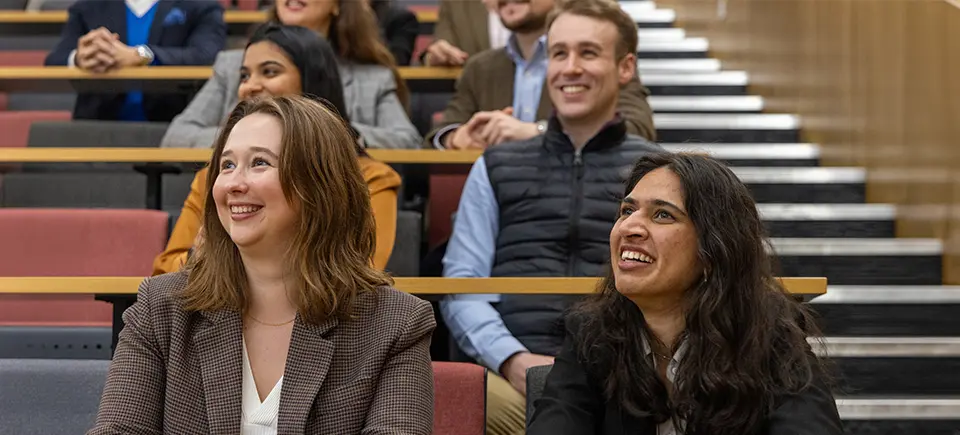 Four students seated in a lecture theatre, appearing engaged during a lecture.