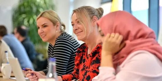 Three women sat in a group in a classroom