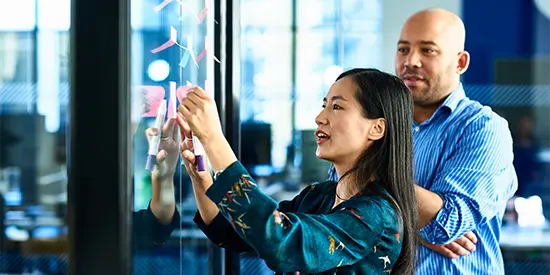 Colleagues in discussion and adding notes to a board