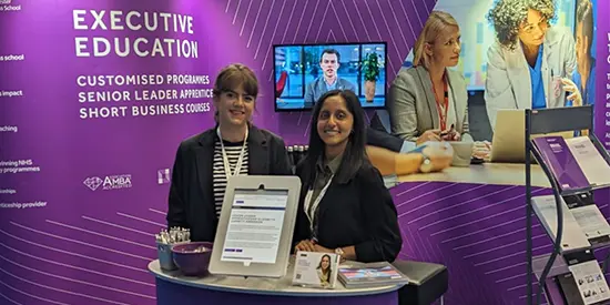 Two professionals standing in front of an exhibition stand at a conference