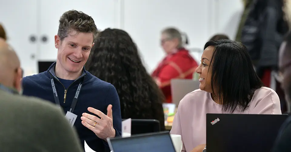 Two delegates smiling and talking to each other during a short business course workshop at Alliance MBS.