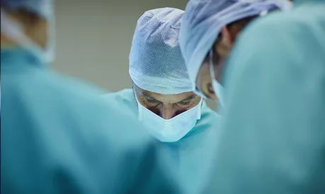 A surgeon in scrubs working during an operation.