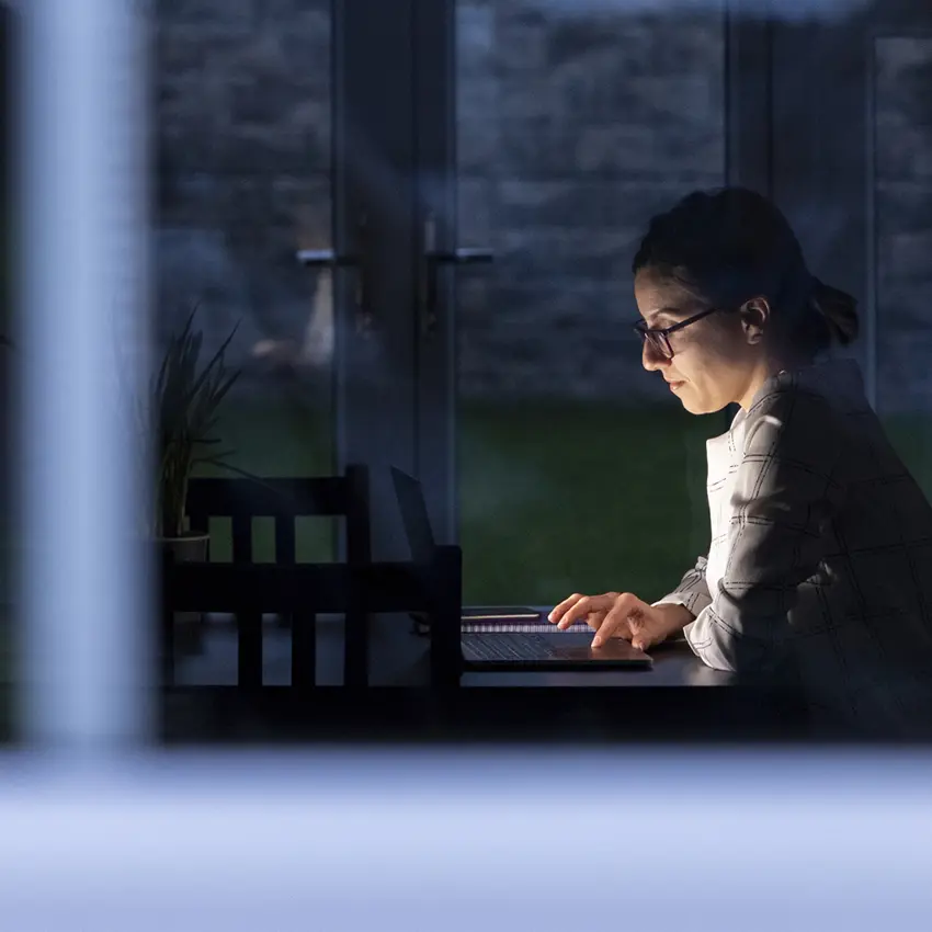 A view outside an office space of a woman working at her desk on her own.