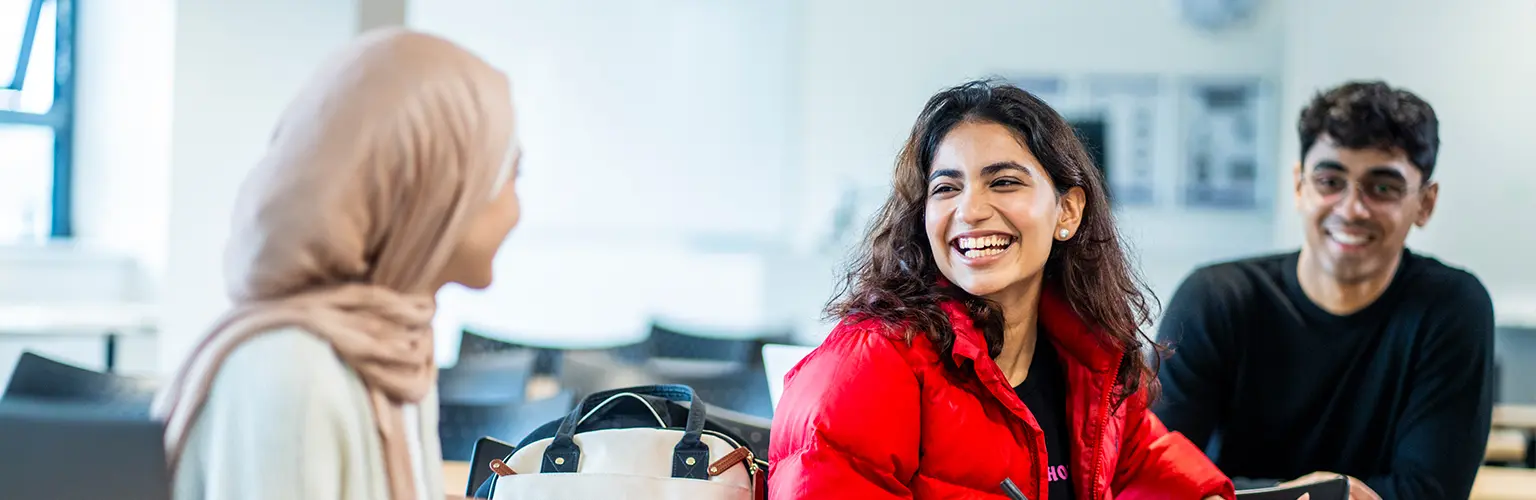 Alliance MBS master's students talking and smiling together in a classroom.