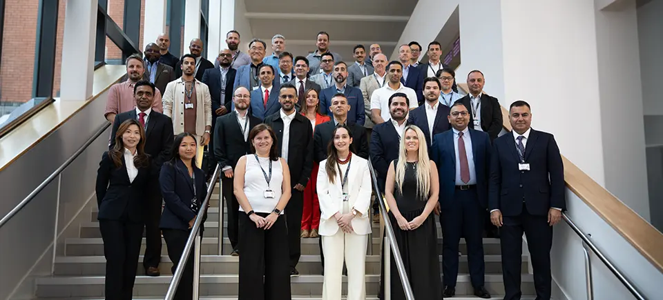 A large group of Global Executive MBA candidates standing on a large stairwell at Alliance MBS.