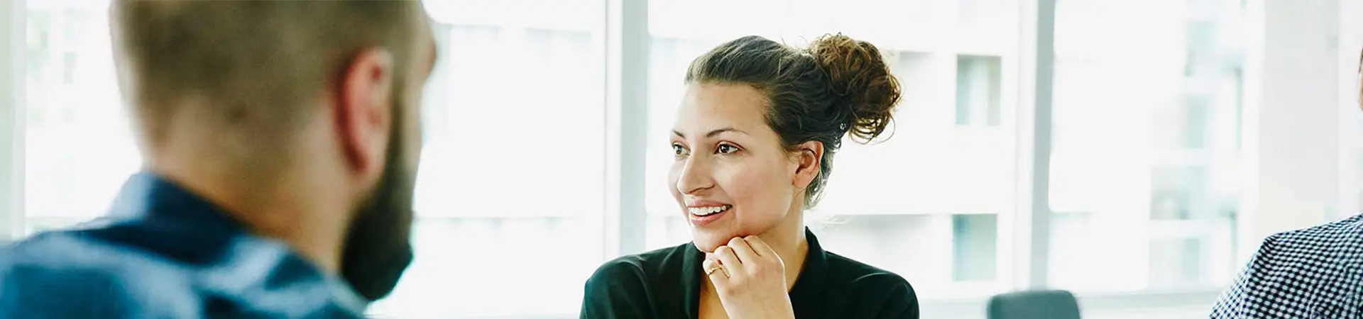 A business woman smiling in a brightly lit office.