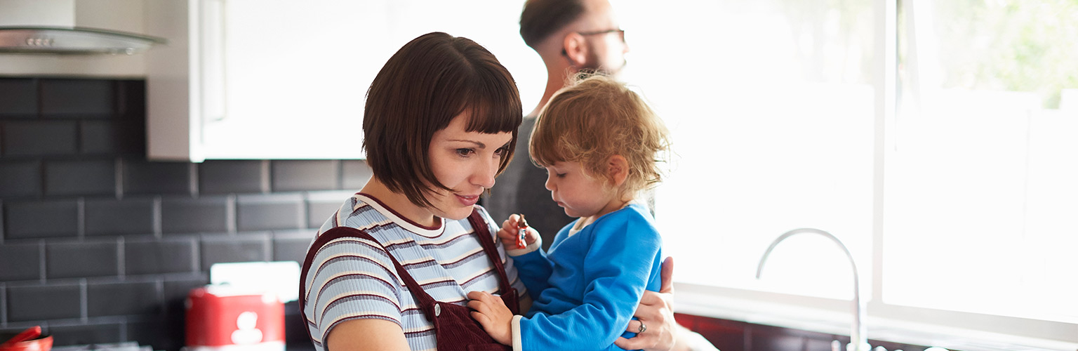 Mother holding child in kitchen young family