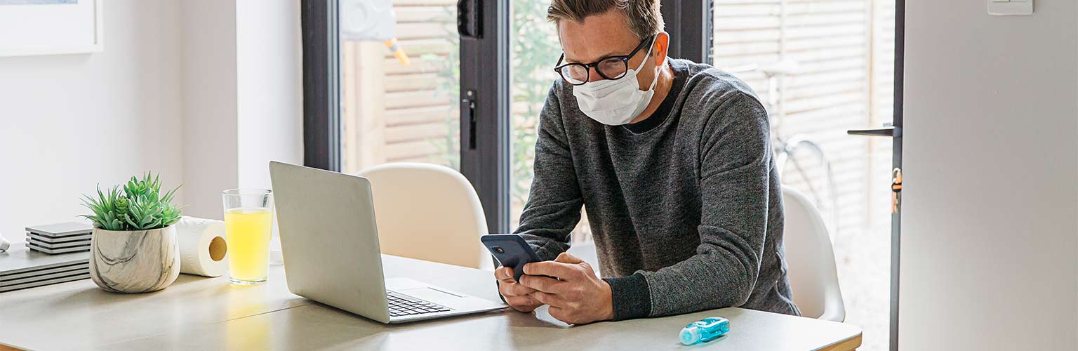 a man working from home with a face mask on 