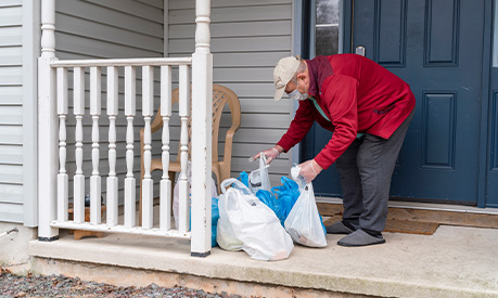 A vulnerable man getting his shopping which has been left on his porch