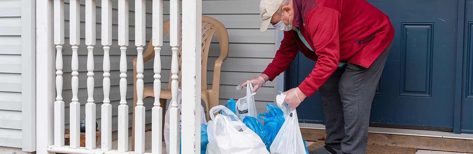 a vulnerable man getting shopping that has been left on his porch