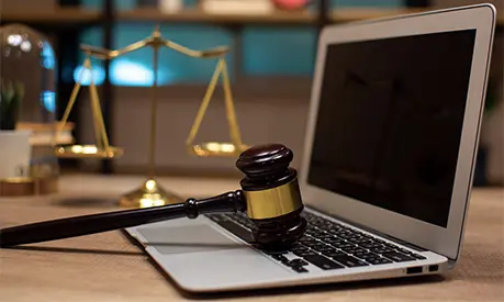law legal technology concept. judge gavel on computer with scales of justice on desk of lawyer
