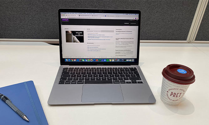 A desk with a laptop and coffee cup on it