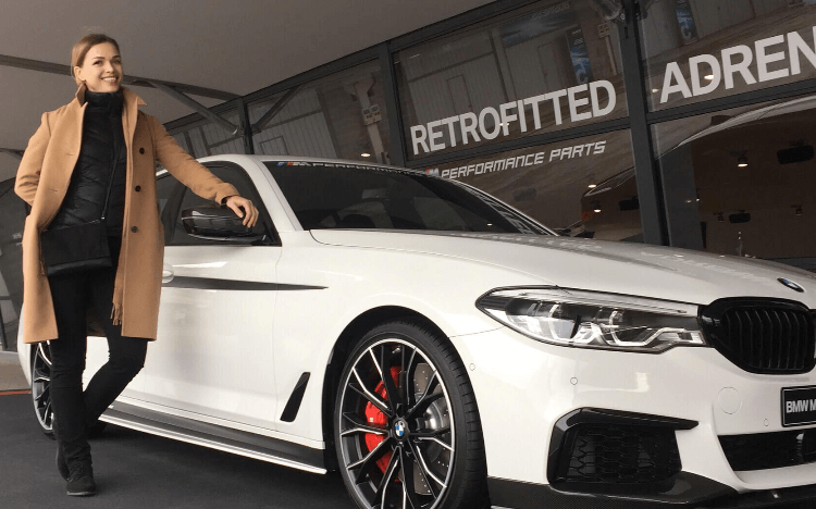 A woman standing next to a white sports car