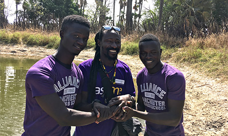 three men standing with alliance manchester business school shirts