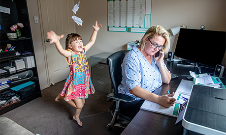 a woman attempting to work from home being distracted by her child