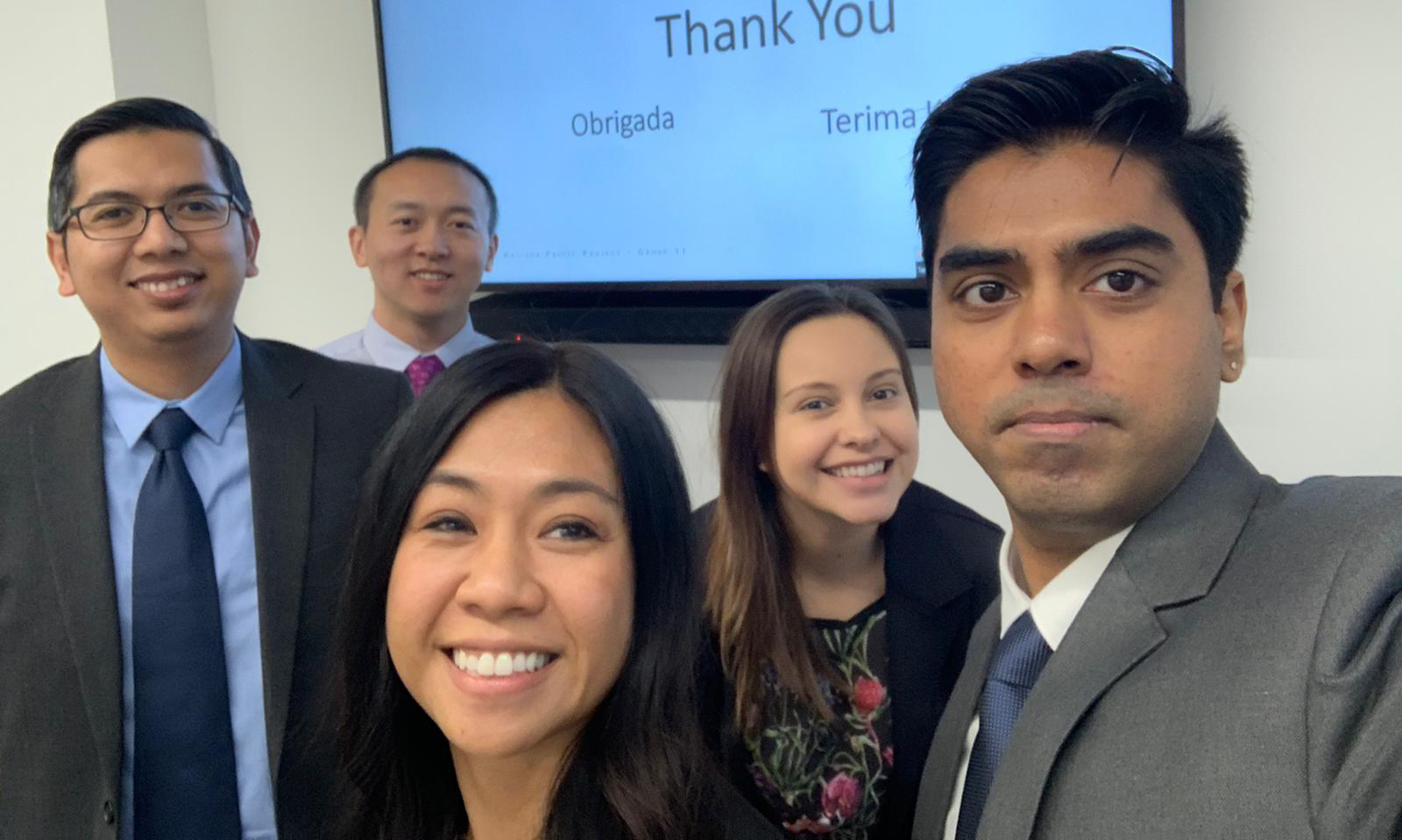 Five MBA candidates smiling at the camera