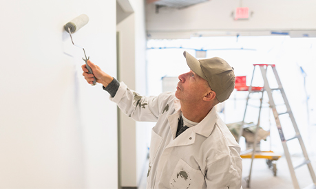 a self employed painter painting a white wall with a roller