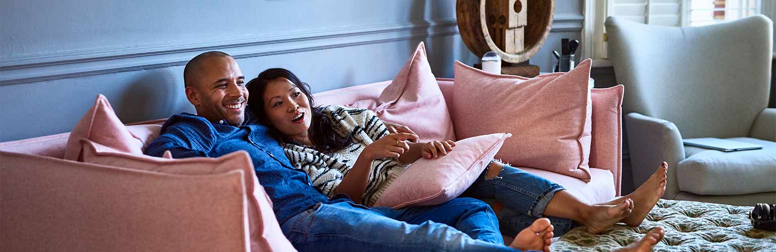 a man and a woman enjoying watching tv on the sofa