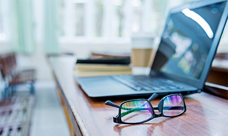 A pair of glasses and a laptop on a desk in an office