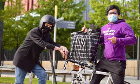 ambs student on a bike delivering supplies 