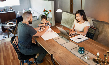 A woman working from home and a man homeschooling his child