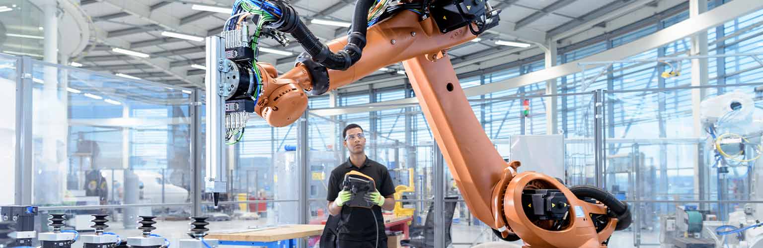 Engineer programming robot in robotics research facility