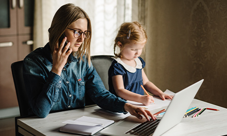 A woman working on her desk with her child next to her