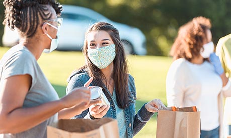  Female volunteers at a community foodbank wearing face coverings