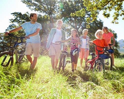 different generations of a family in one picture with the sun shining in a park