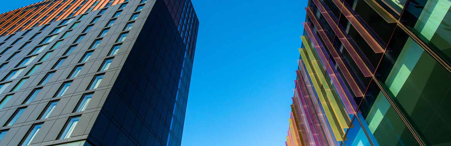 A photo of the multi-coloured glass fins above the main entrance of Alliance MBS and a blue sky