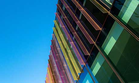 A photo of the multi-coloured glass fins above the main entrance of Alliance MBS and a blue sky