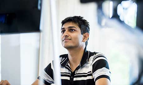 Male Master's student looking at a computer screen