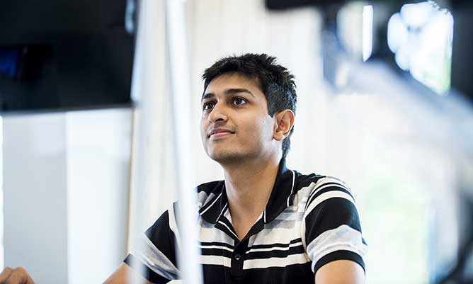 Male Master's student looking at a computer screen