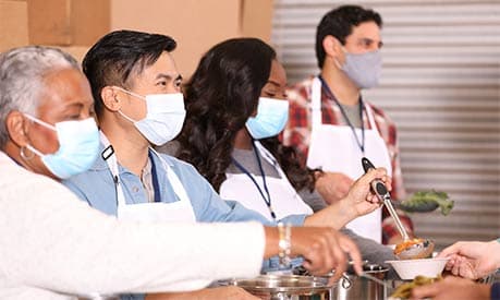 volunteers in masks helping out at a soup kitchen