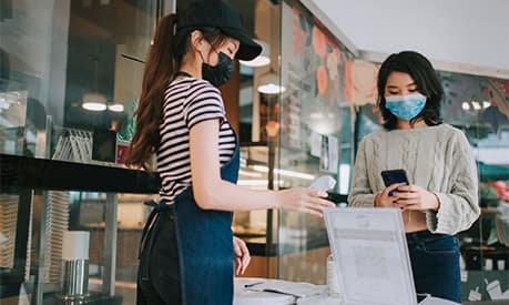 A woman wearing a mask using her phone to log in to a track and trace app