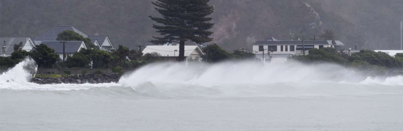A wave crashing into the shore during high tide and strong winds