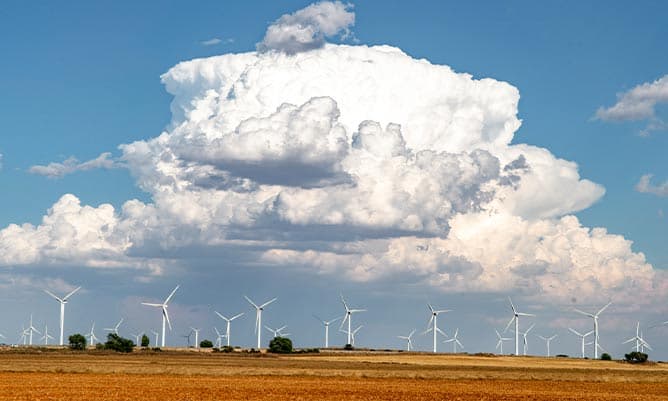A large windfarm with a huge cloud forming above them