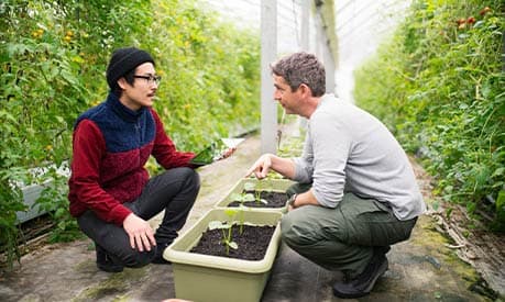 A manager and employee outside with a tablet in a farm